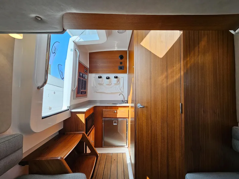 Slide: The Image of 2025 Southport 38 FE boat interior with modern wood finish and compact kitchen area. - 11
