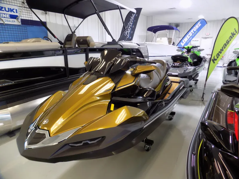 Slide: The Image of 2023 Kawasaki 310 LX jet ski in showroom, gold and black design, surrounded by boats and banners. - 2