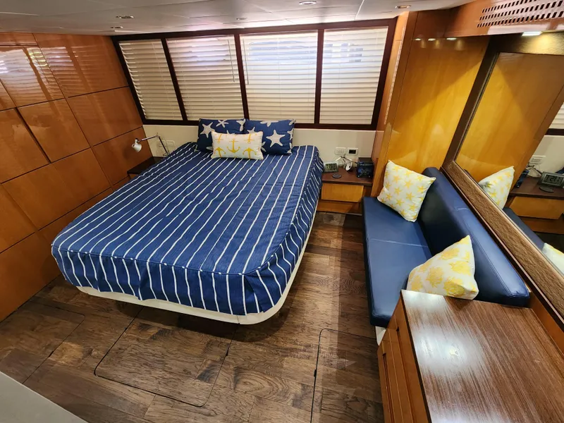 Slide: The Image of Luxurious bedroom in a 2006 Pershing Cruiser with wooden accents and striped bedding. - 25
