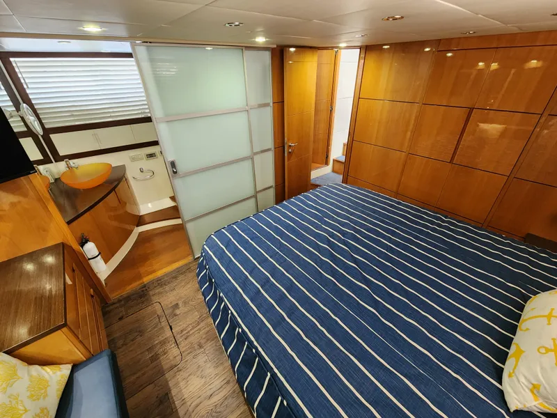 Slide: The Image of Luxurious bedroom on a 2006 Pershing Cruiser with modern wooden interior and en-suite bathroom. - 27