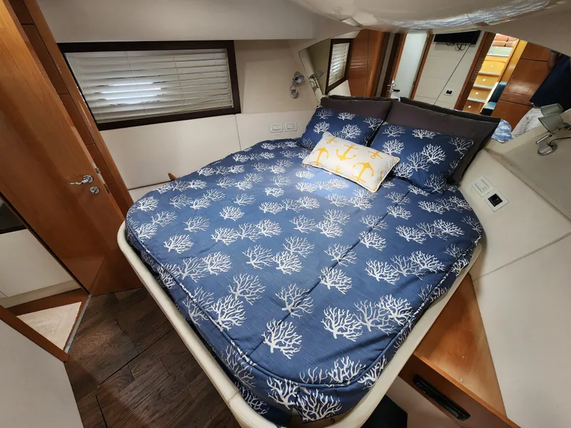 Slide: The Image of Luxurious bedroom in a 2006 Pershing Cruiser yacht with nautical-themed bedding. - 34