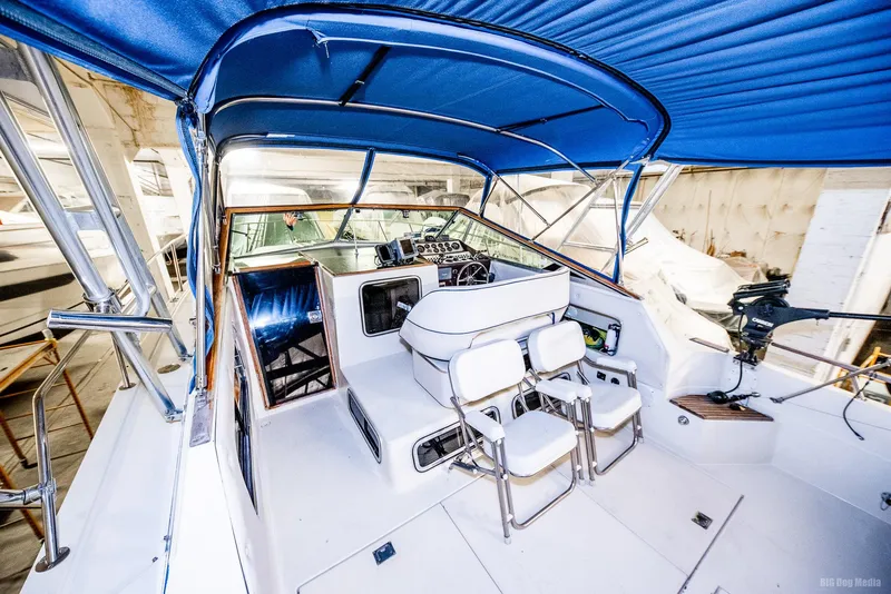 Slide: The Image of 1985 Chris-Craft 336 Mid Cabin boat interior with blue canopy and white seating. - 22