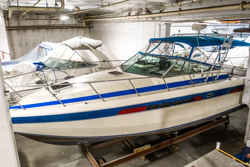 Slide: The Image of 1985 Chris-Craft 336 Mid Cabin boat in indoor storage, featuring blue and white design. - 4