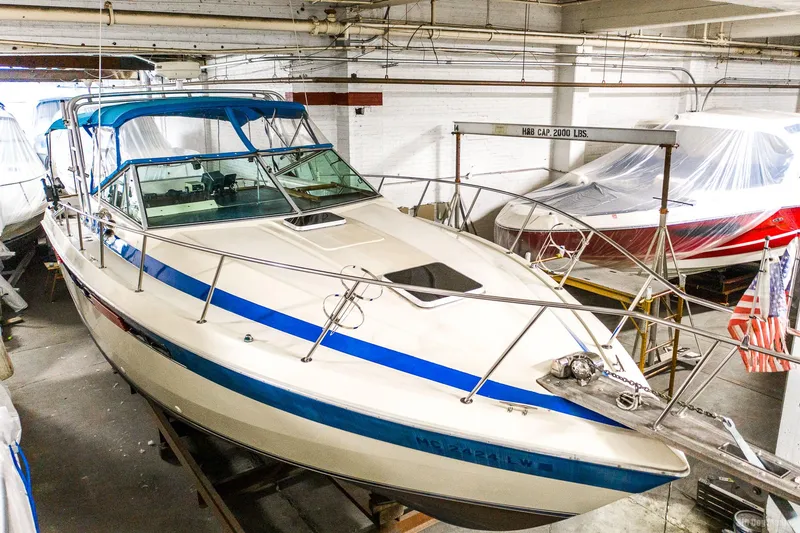 Slide: The Image of 1985 Chris-Craft 336 Mid Cabin boat in storage, featuring blue accents and covered interior. - 5