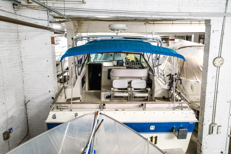Slide: The Image of 1985 Chris-Craft 336 Mid Cabin boat in storage with blue canopy. - 6