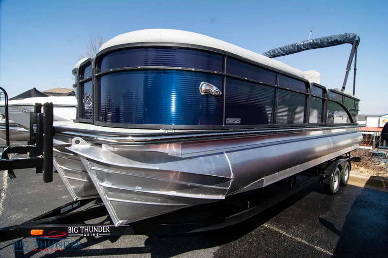 Slide: The Image of 2022 Manitou 25 OASIS RF SHP pontoon boat on trailer, blue and silver design. - 0