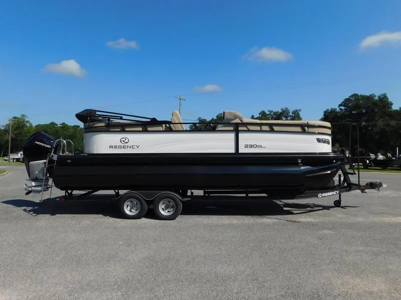 Slide: The Image of 2023 Regency 230 DL3 pontoon boat on a trailer under a clear blue sky. - 0