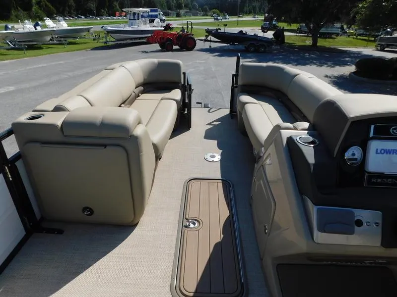Slide: The Image of 2023 Regency 230 DL3 pontoon boat interior with beige seating and control console. - 10