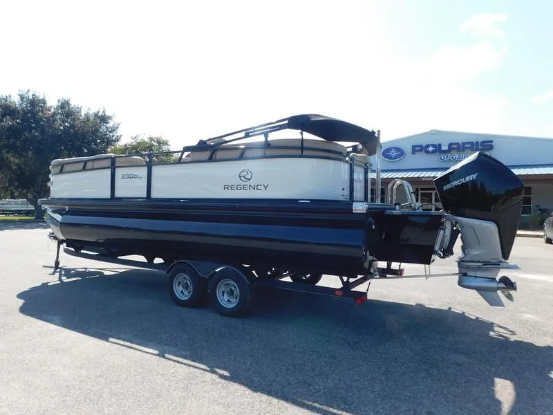 Slide: The Image of 2023 Regency 230 DL3 pontoon boat on trailer outside Polaris dealership. - 5