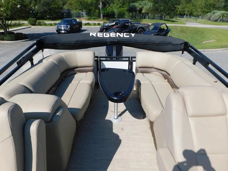 Slide: The Image of 2023 Regency 230 DL3 pontoon boat with beige seating and black canopy. - 8