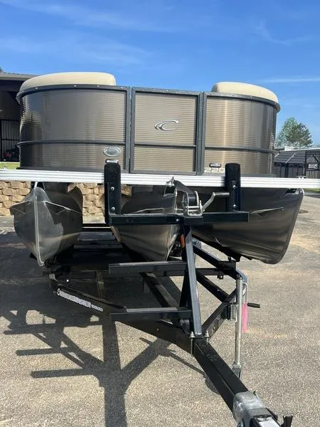 The Image of 2023 Crest Classic DLX 220 SLRC pontoon boat on trailer, parked outdoors. - 1