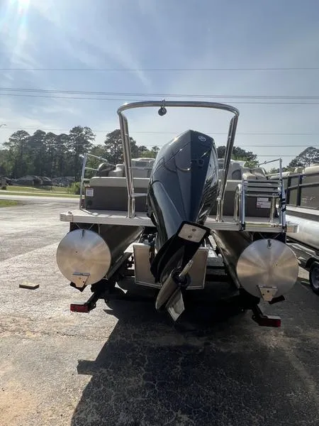 Slide: The Image of 2023 Crest Classic DLX 220 SLRC pontoon boat, rear view with motor, parked outdoors. - 5