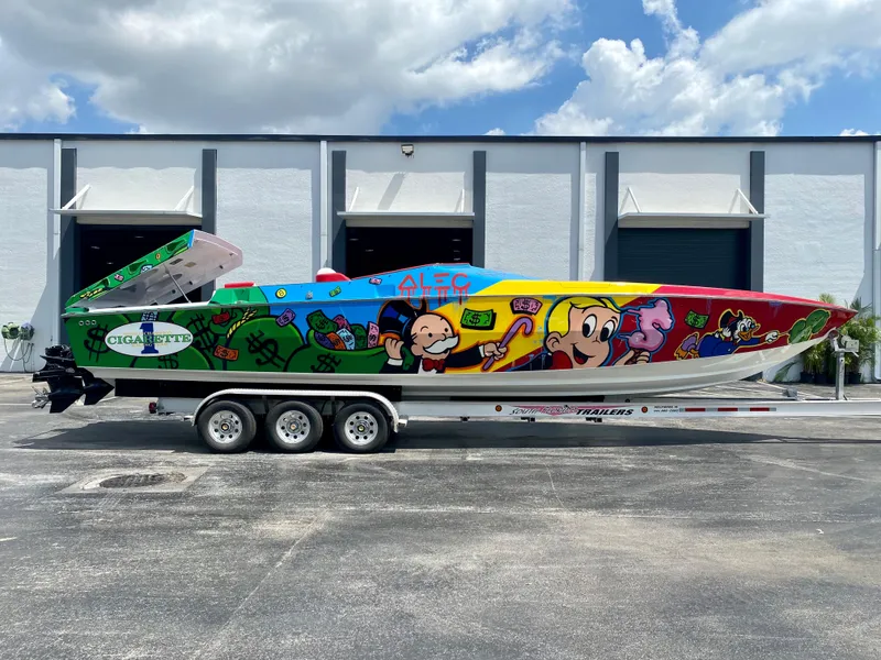 The Image of 2023 Cigarette 35 Cafe Racer boat with colorful cartoon graphics, parked outdoors. - 0