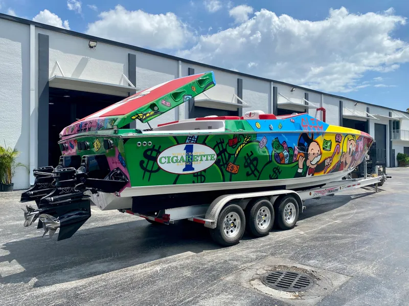 Slide: The Image of 2023 Cigarette 35 Cafe Racer boat with vibrant graffiti art on a trailer. - 2