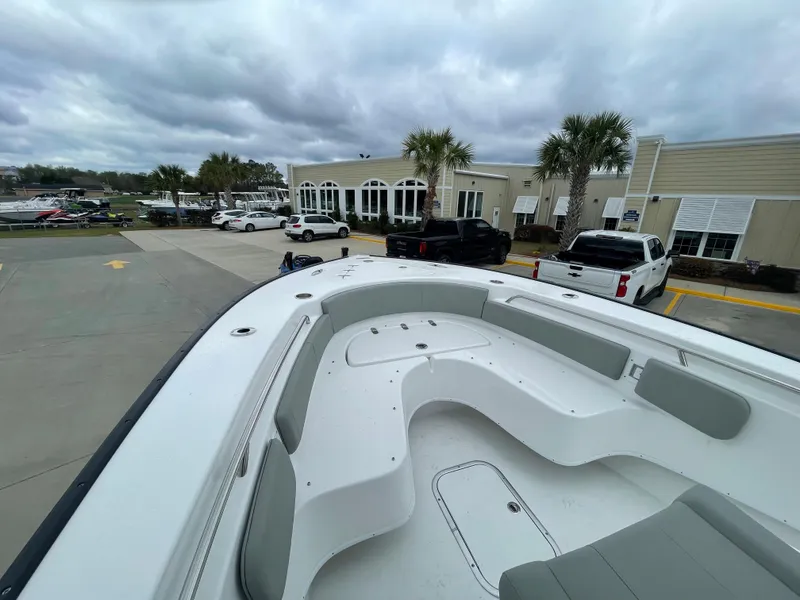 Slide: The Image of 2026 Cape Horn 24XS boat with spacious seating, parked near a building under cloudy skies. - 11