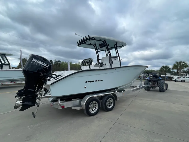 Slide: The Image of 2026 Cape Horn 24XS boat on trailer with Suzuki outboard motor, parked outdoors. - 2
