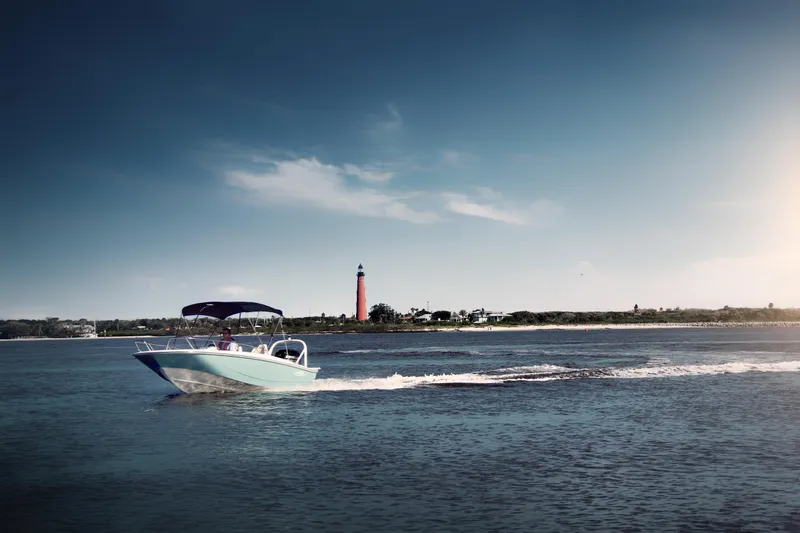 Slide: The Image of 2024 Boston Whaler 160 Super Sport cruising on water near a lighthouse under a clear sky. - 4