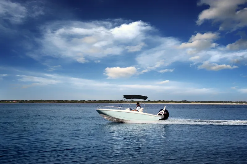 Slide: The Image of 2024 Boston Whaler 160 Super Sport cruising on open water under a clear blue sky. - 5
