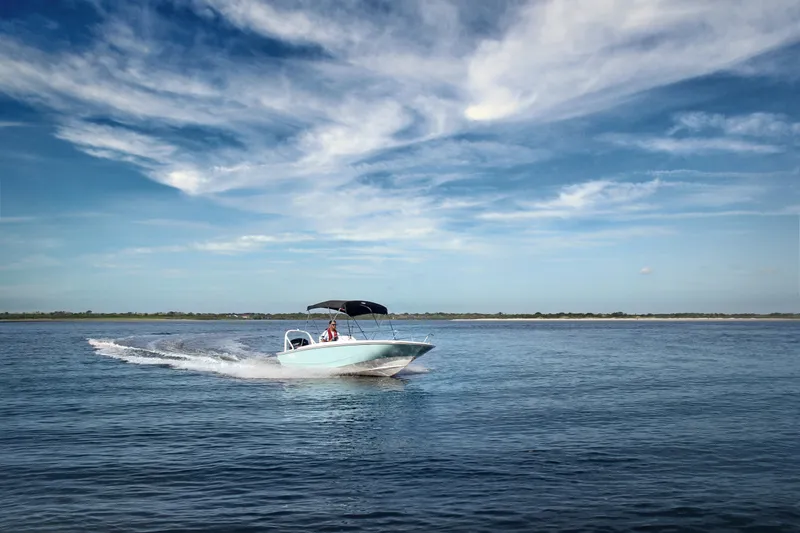 Slide: The Image of 2024 Boston Whaler 160 Super Sport cruising on open water under a blue sky. - 6