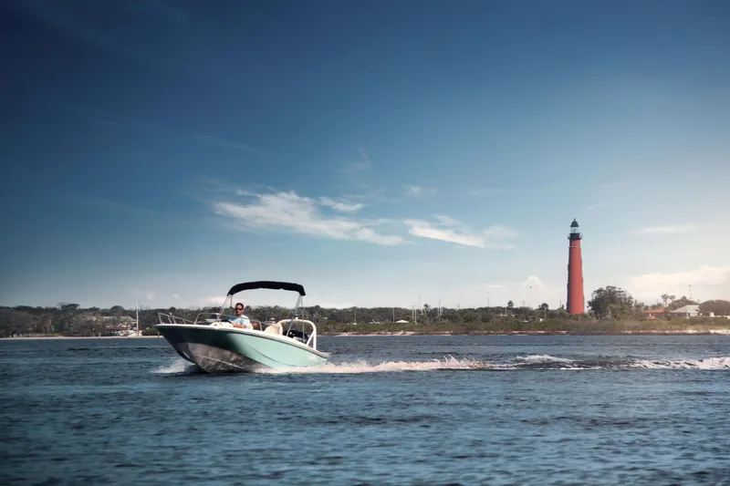 Slide: The Image of 2024 Boston Whaler 160 Super Sport cruising near a lighthouse on a sunny day. - 9