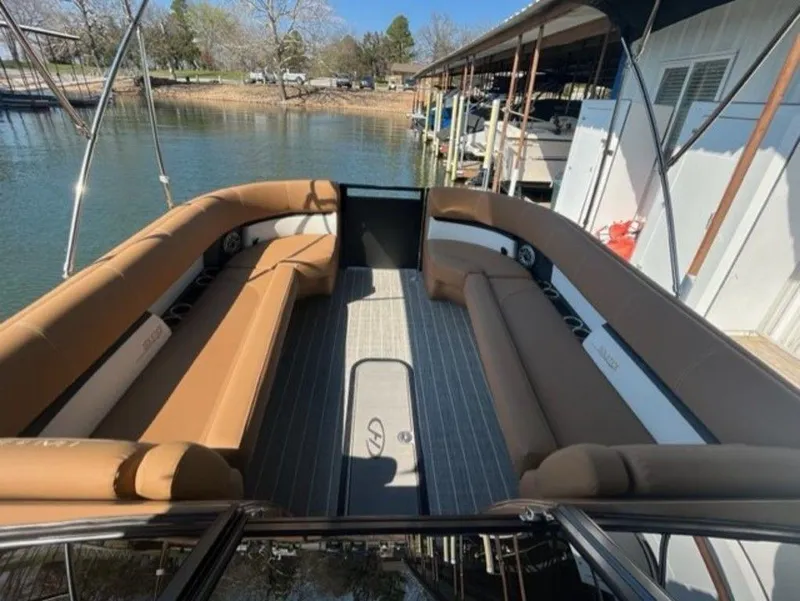 Slide: The Image of 2023 Harris Solstice DC 250 SLDH pontoon boat with spacious seating, docked by a serene lake. - 14