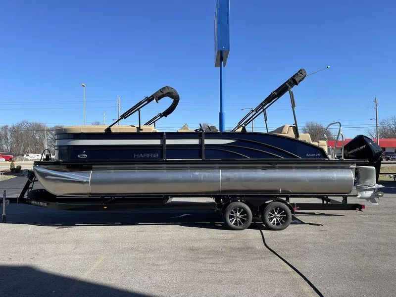 Slide: The Image of 2023 Harris Sunliner 250 pontoon boat on trailer, parked outdoors under clear blue sky. - 21
