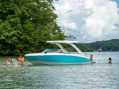 Slide: The Image of 2023 Regal LS4 Surf boat on a lake with people swimming nearby. - 1