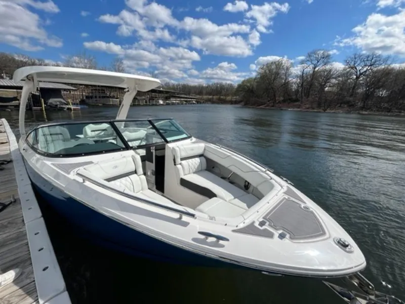 Slide: The Image of 2023 Regal LS6 boat docked on a serene lake under a partly cloudy sky. - 13