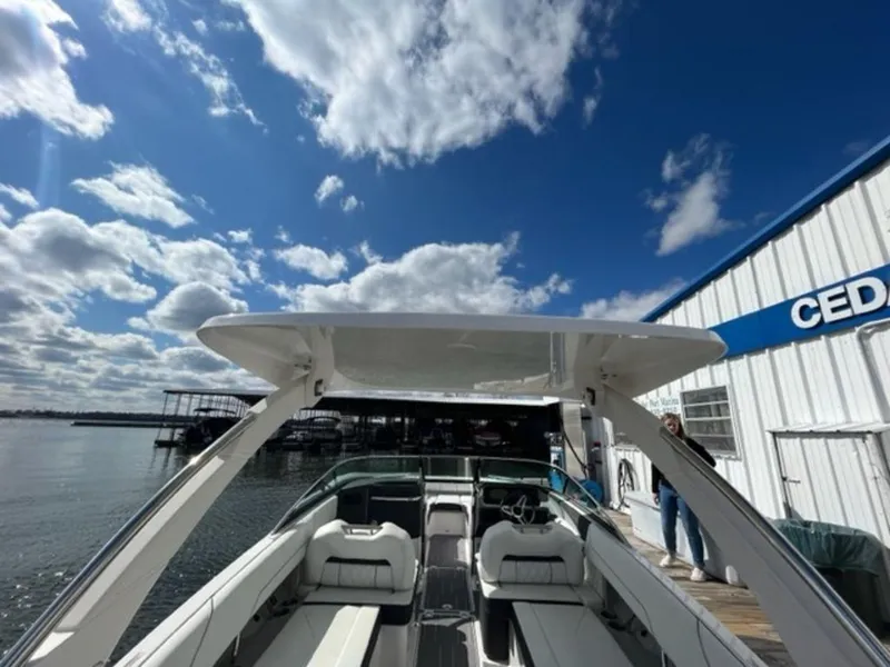 Slide: The Image of 2023 Regal LS6 boat docked under a bright blue sky with clouds. - 2