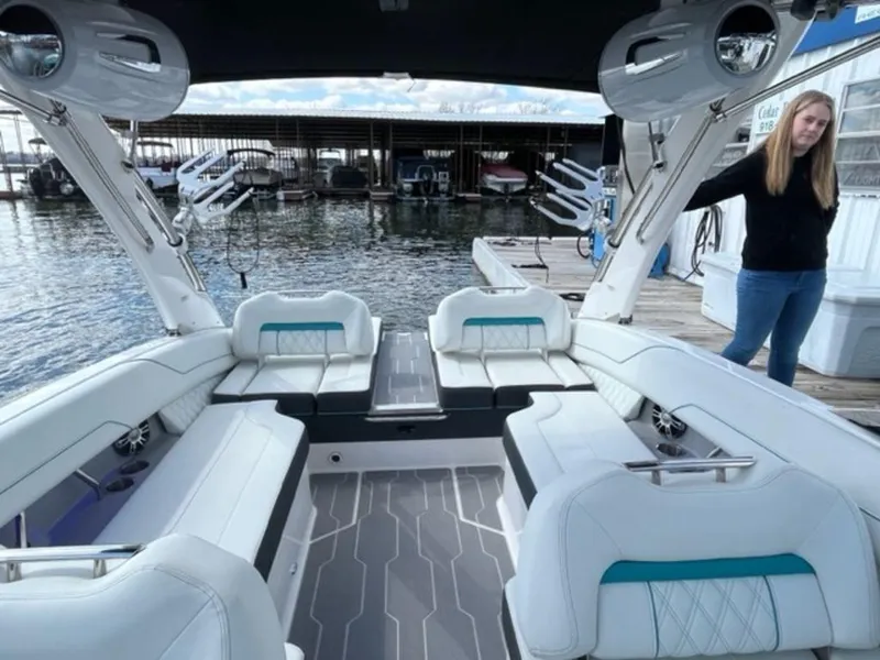 Slide: The Image of 2023 Regal LS6 Surf boat interior with white seating and modern design at a dock. - 10