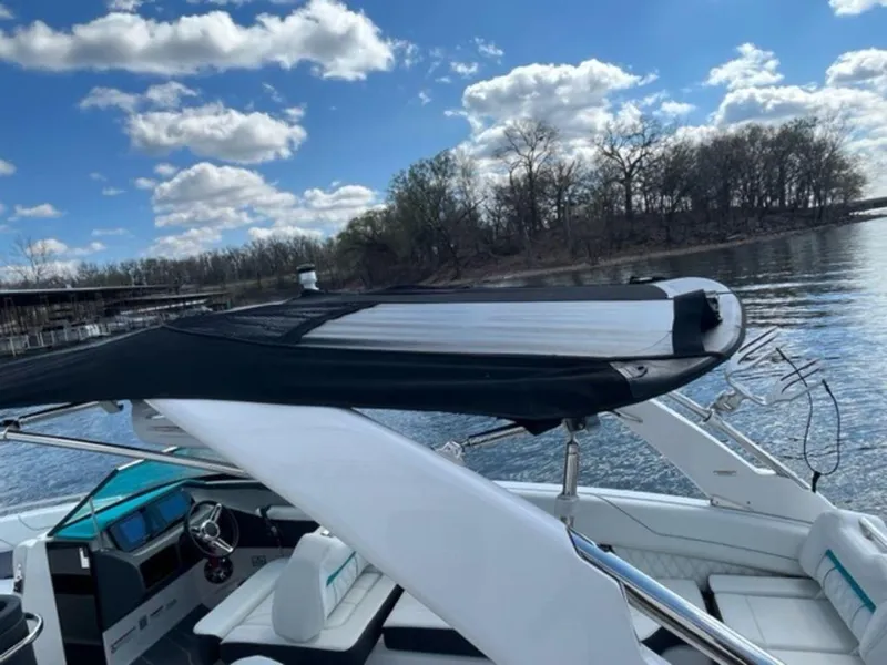 Slide: The Image of 2023 Regal LS6 Surf boat on a serene lake under a blue sky. - 22