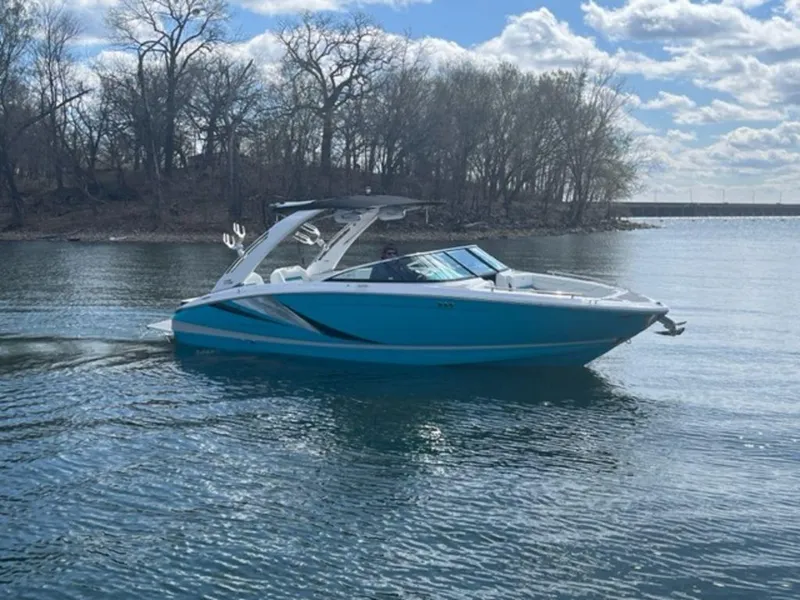 Slide: The Image of 2023 Regal LS6 Surf boat cruising on a calm lake under a partly cloudy sky. - 6