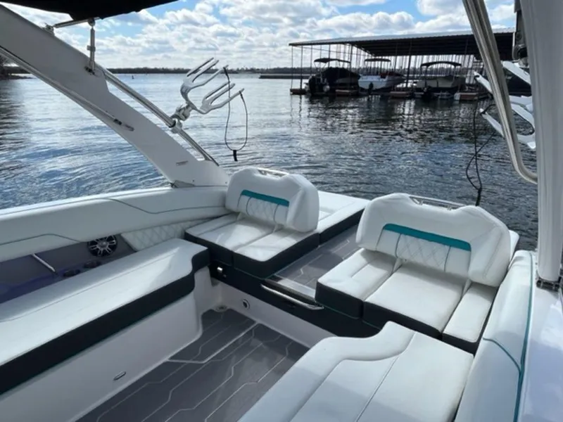 Slide: The Image of 2023 Regal LS6 Surf boat interior with white seating, docked by a marina. - 9