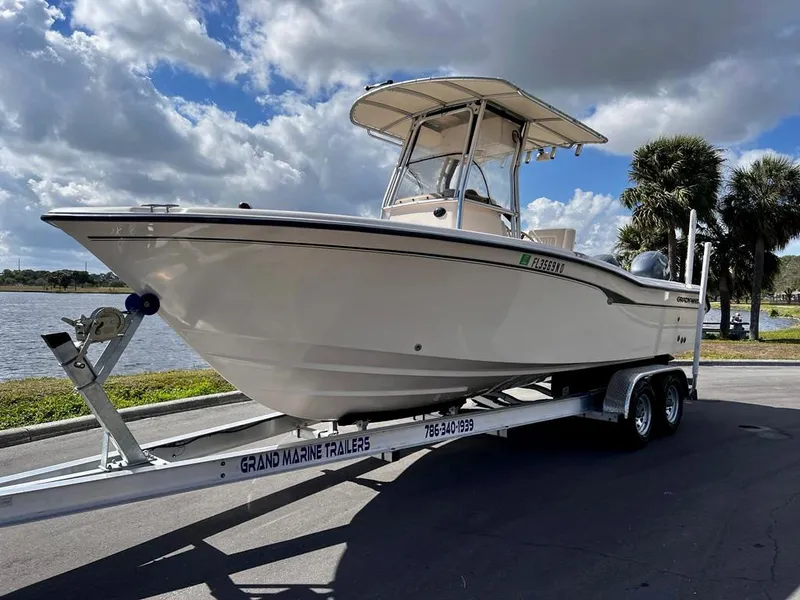 Slide: The Image of 2005 Grady-White 257 Advance boat on trailer, parked near a lake under a cloudy sky. - 2