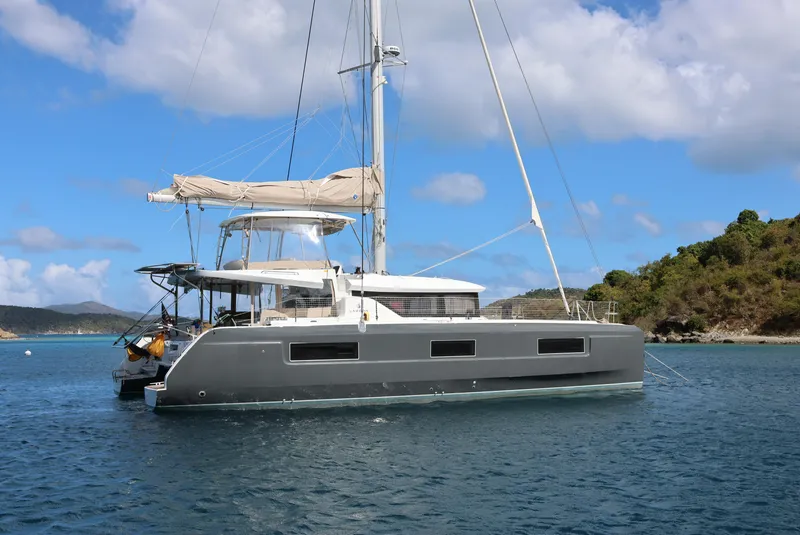 The Image of 2022 Lagoon 46 catamaran sailing in clear blue waters near a lush island. - 0