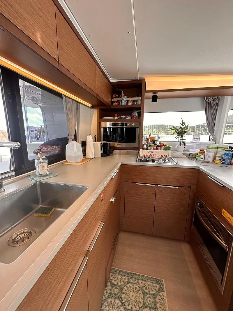 Slide: The Image of Modern kitchen interior of 2022 Lagoon 46 catamaran with wood cabinetry and appliances. - 12