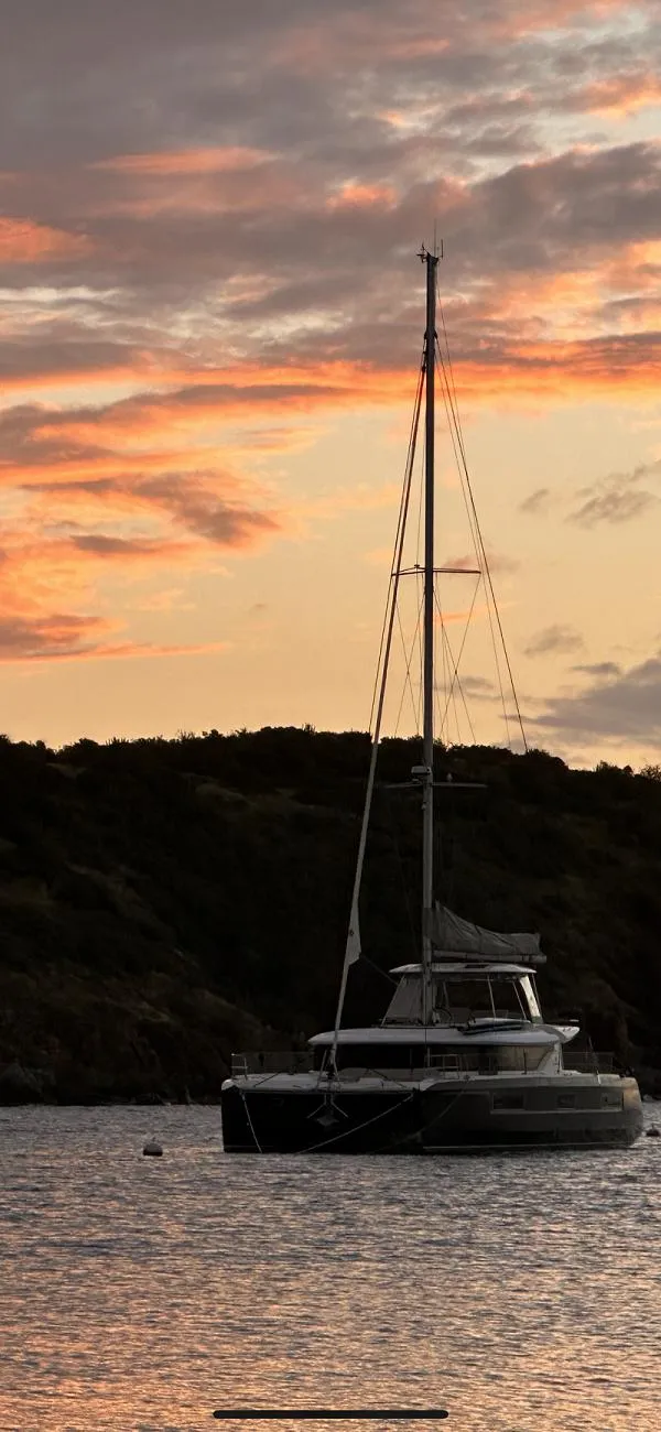 Slide: The Image of Lagoon 46 catamaran at sunset, 2022 model, anchored in tranquil waters. - 23