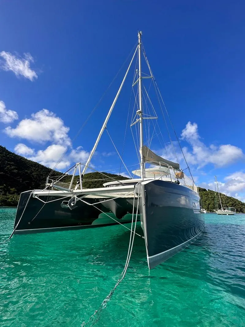 Slide: The Image of 2022 Lagoon 46 catamaran anchored in clear turquoise water under a bright blue sky. - 4