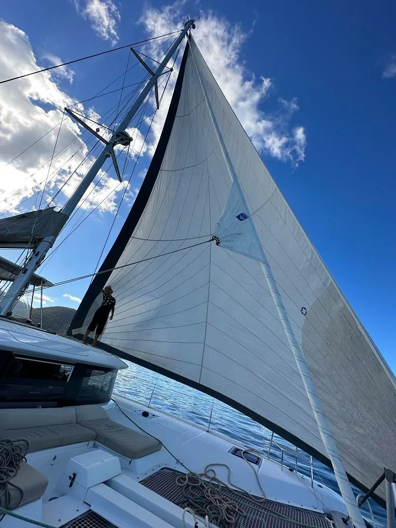 Slide: The Image of 2022 Lagoon 46 sailboat with full sails against a clear blue sky. - 8