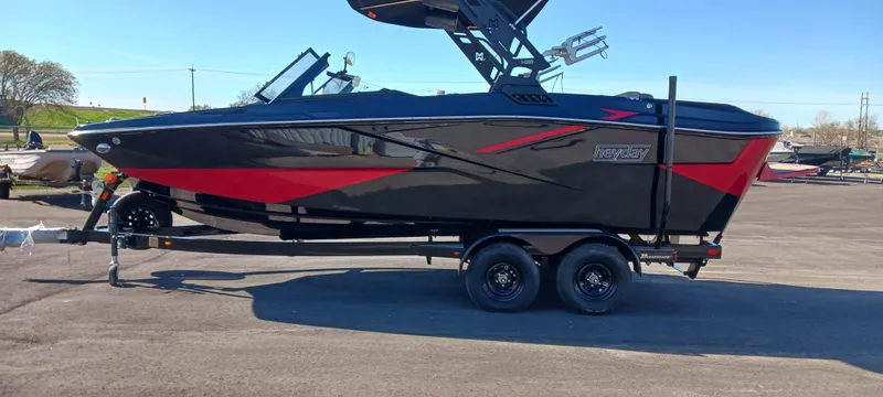 Slide: The Image of 2023 Heyday H22 boat on trailer, black and red design, parked outdoors. - 2