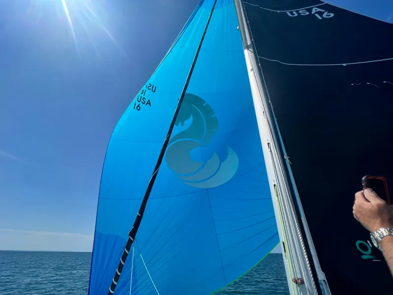 Slide: The Image of 2023 Beneteau First 36 sailboat with blue and black sails on open water. - 10