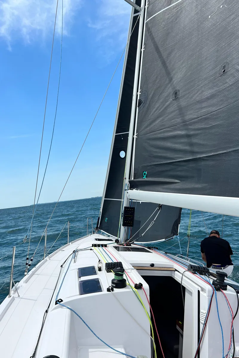 Slide: The Image of 2023 Beneteau First 36 sailboat on open water with black sails. - 12