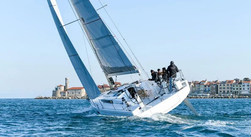 Slide: The Image of 2023 Beneteau First 36 sailboat navigating near coastal town. - 18