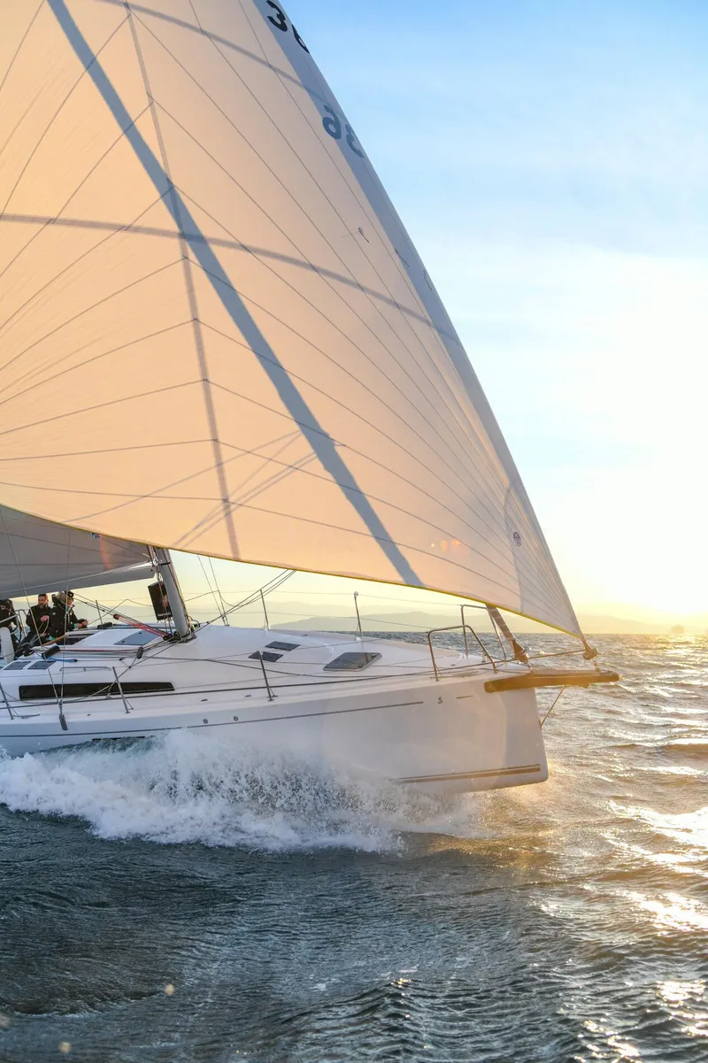 Slide: The Image of 2023 Beneteau First 36 sailboat navigating ocean waves at sunset. - 23