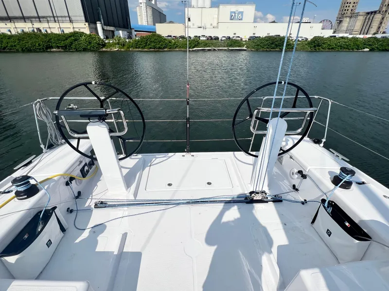 Slide: The Image of 2023 Beneteau First 36 sailboat cockpit with dual steering wheels, docked by industrial buildings. - 6