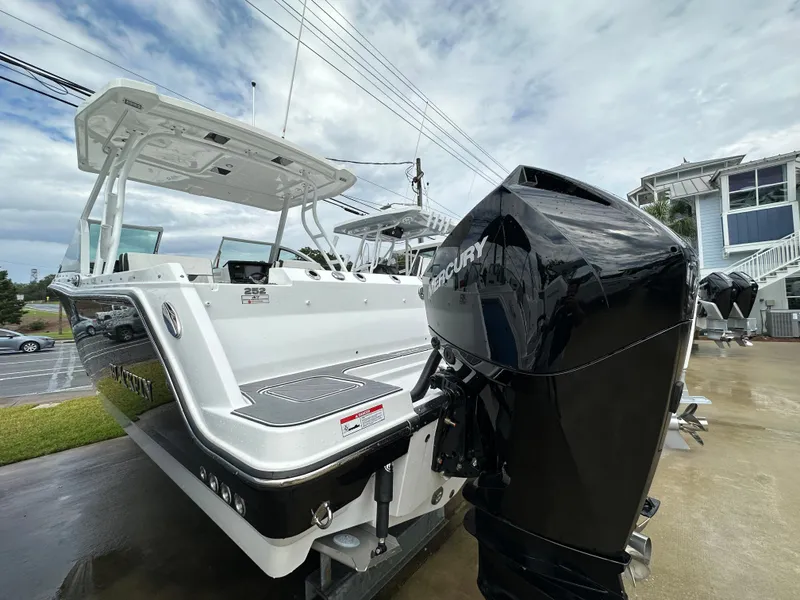 Slide: The Image of 2023 Blackfin 252 DC boat with Mercury outboard engine, docked on a concrete surface. - 2