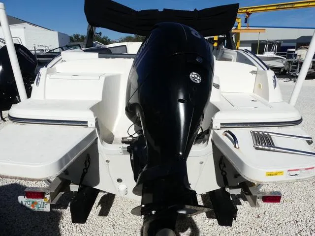Slide: The Image of 2018 Bayliner 210 Deck Boat with outboard motor, rear view in a marina setting. - 5