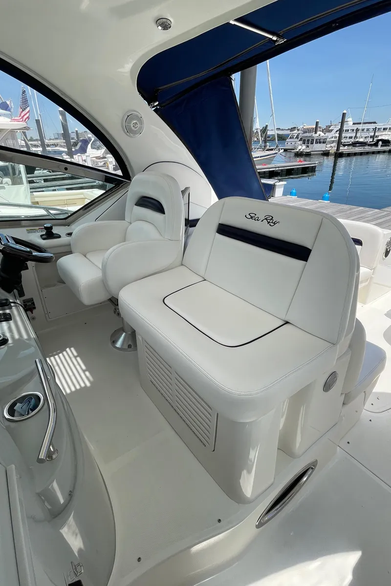 Slide: The Image of 2011 Sea Ray 390 Sundancer cockpit with white seating, marina view in background. - 20