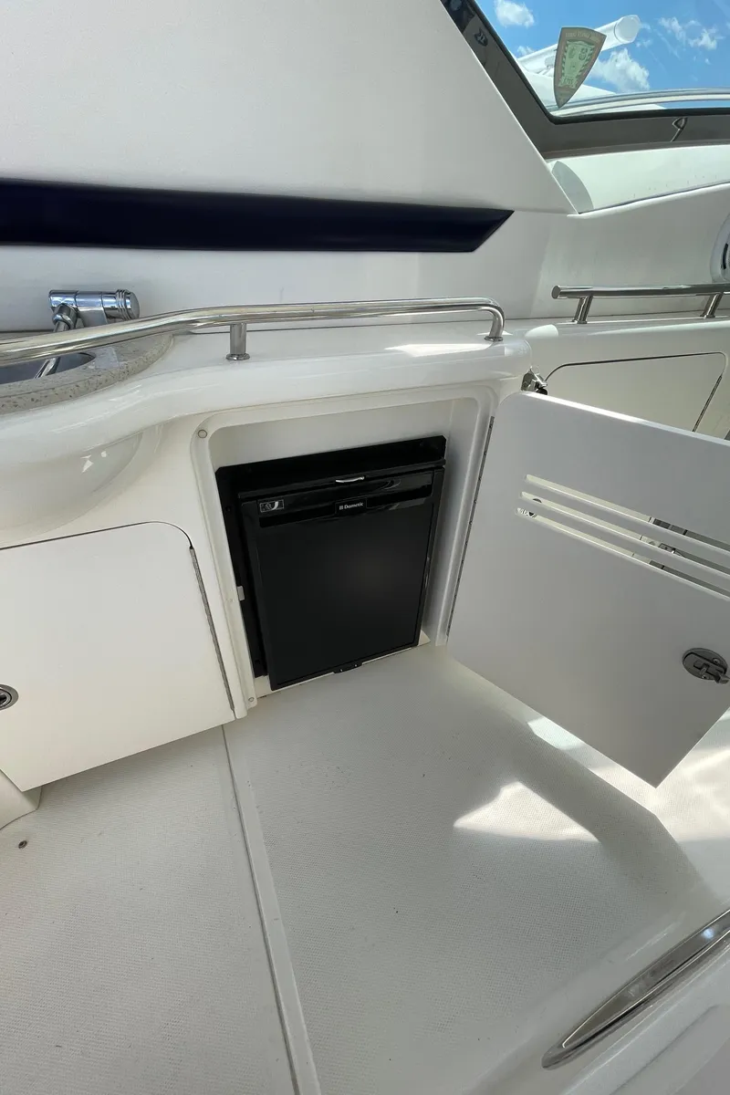 Slide: The Image of 2011 Sea Ray 390 Sundancer interior with open cabinet and mini fridge. - 23