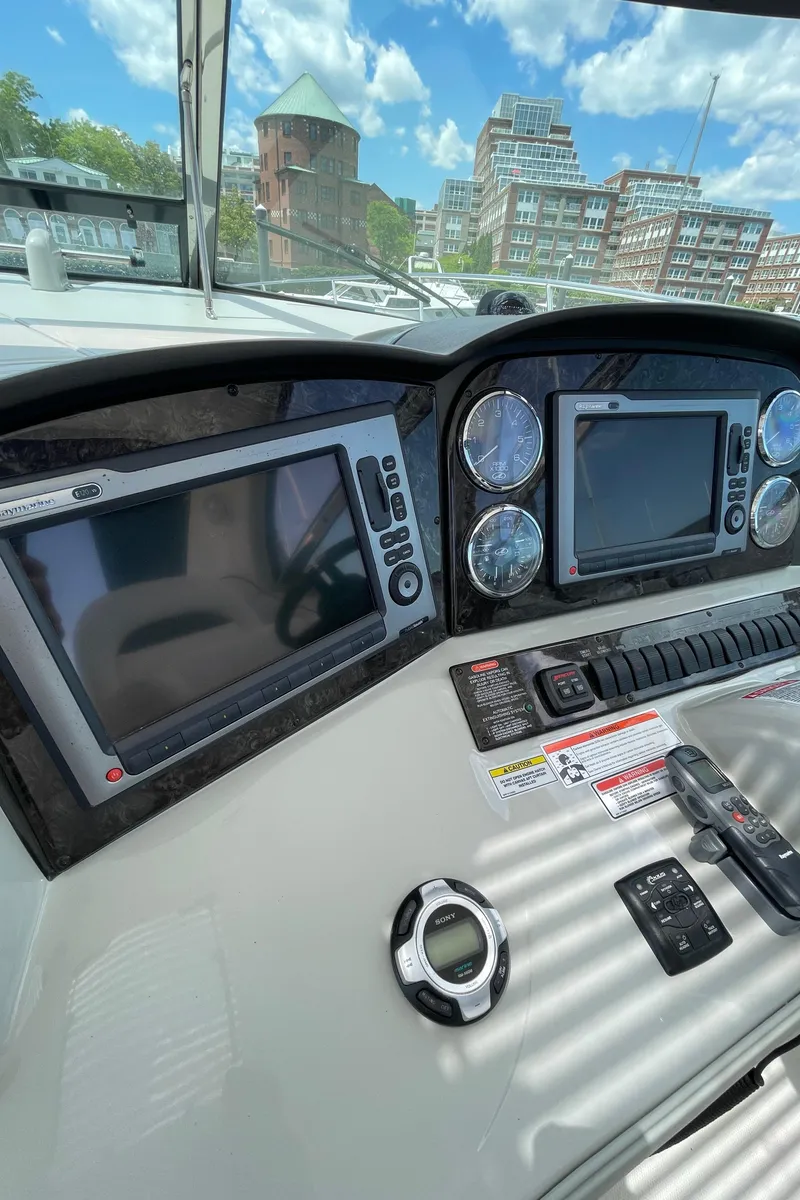 Slide: The Image of 2011 Sea Ray 390 Sundancer helm with navigation screens and controls, cityscape in background. - 27
